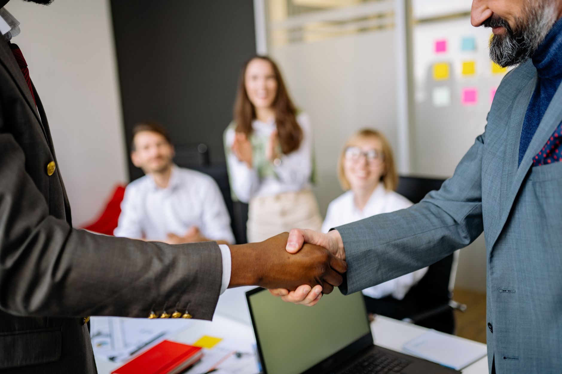 Two people shaking hands over documents at a desk